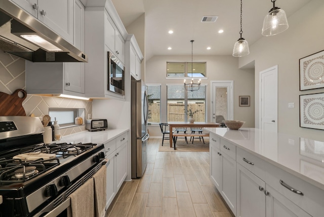 kitchen featuring white cabinets, stainless steel appliances, decorative light fixtures, and a notable chandelier