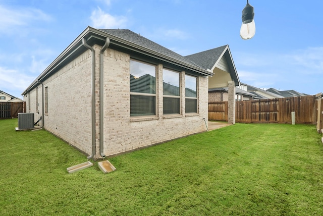 view of side of home with central AC and a lawn