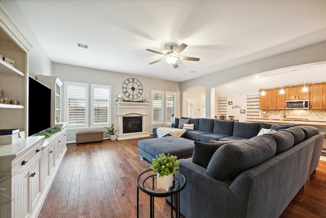 living room with ceiling fan and dark wood-type flooring