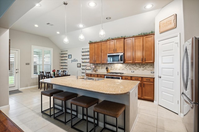 kitchen featuring sink, stainless steel appliances, pendant lighting, vaulted ceiling, and a kitchen island with sink