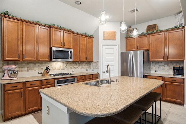 kitchen featuring a kitchen breakfast bar, sink, stainless steel appliances, and a kitchen island with sink