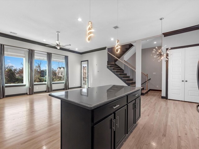 kitchen with ornamental molding, a kitchen island, hanging light fixtures, and light hardwood / wood-style floors