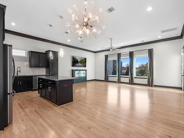 kitchen with sink, a center island, light hardwood / wood-style flooring, ceiling fan with notable chandelier, and appliances with stainless steel finishes