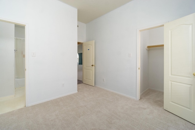 unfurnished bedroom featuring light colored carpet, a spacious closet, and a closet