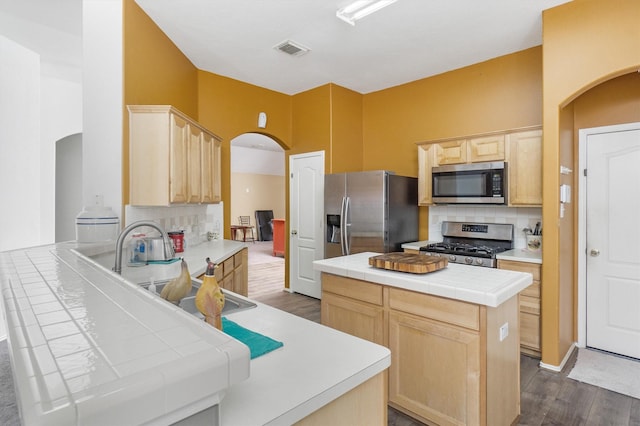 kitchen with backsplash, sink, light brown cabinetry, appliances with stainless steel finishes, and tile counters