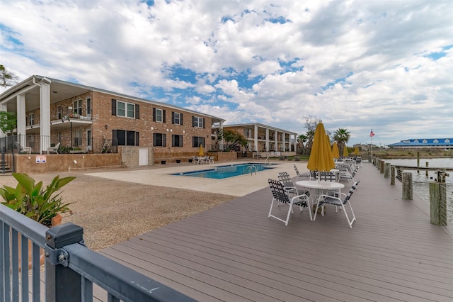 view of swimming pool with a boat dock, a patio, and a water view