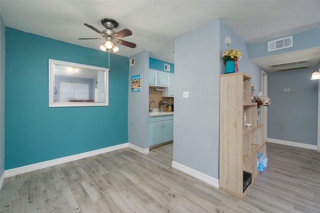 interior space with ceiling fan, sink, and light hardwood / wood-style floors