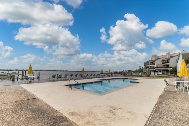 view of pool featuring a water view and a patio