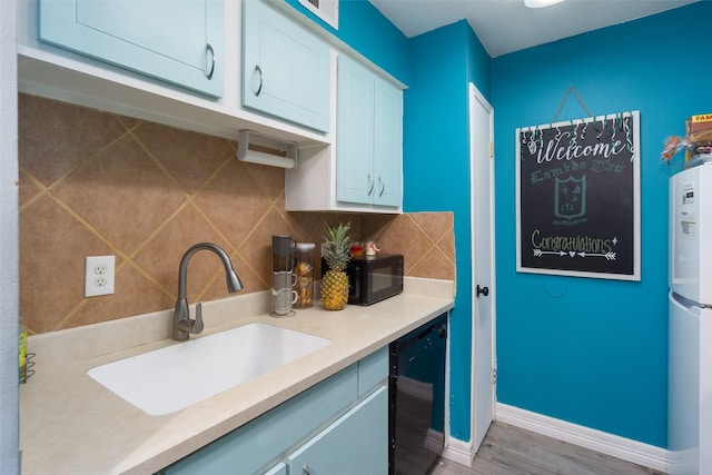 kitchen with sink, wood-type flooring, decorative backsplash, white cabinets, and black appliances