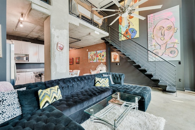 living room featuring ceiling fan, brick wall, and track lighting