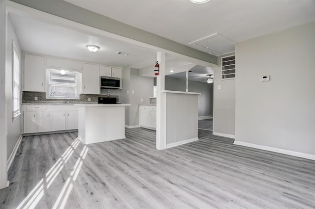 kitchen with white cabinets, decorative backsplash, light wood-type flooring, and sink