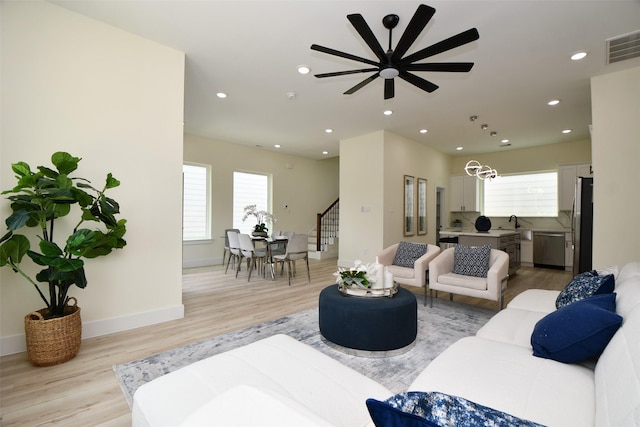 living room featuring ceiling fan, sink, and light hardwood / wood-style floors