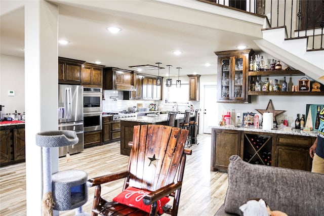 kitchen with pendant lighting, tasteful backsplash, light hardwood / wood-style floors, dark brown cabinetry, and stainless steel appliances