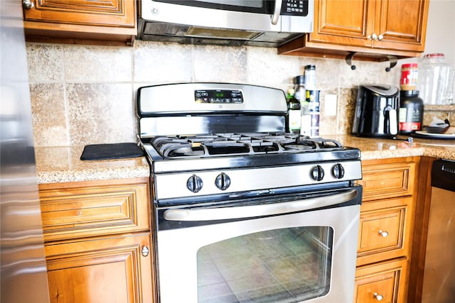 kitchen with decorative backsplash, stainless steel appliances, and light stone counters