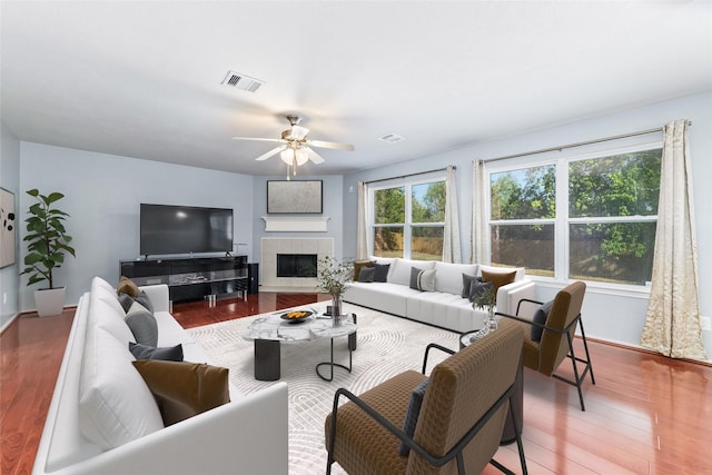 living room featuring a fireplace, wood-type flooring, and ceiling fan