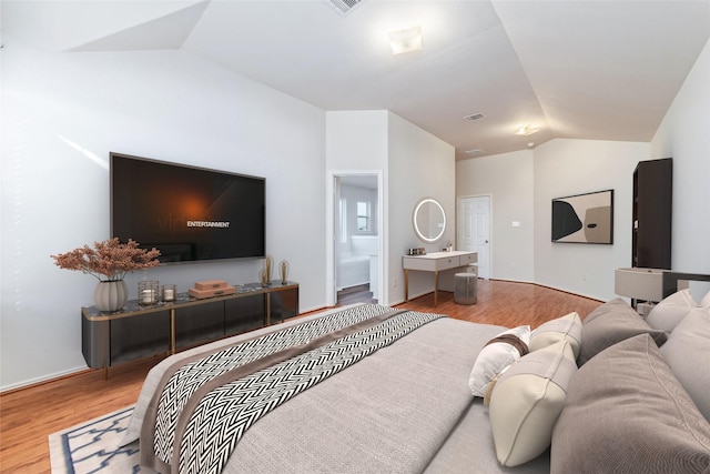 bedroom featuring light wood-type flooring, connected bathroom, and vaulted ceiling