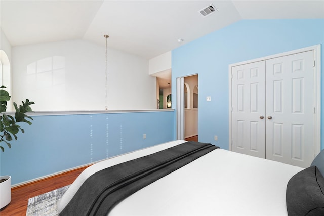 bedroom with a closet, wood-type flooring, and vaulted ceiling