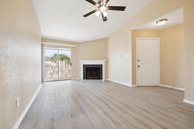 unfurnished living room with a tile fireplace, light wood-type flooring, and ceiling fan