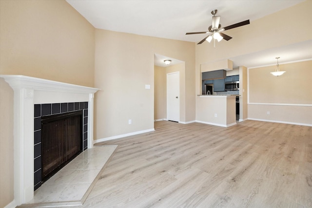 unfurnished living room featuring ceiling fan, a fireplace, lofted ceiling, and light wood-type flooring