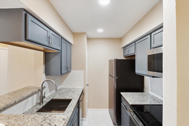 kitchen featuring gray cabinetry, sink, decorative backsplash, light stone countertops, and stainless steel appliances