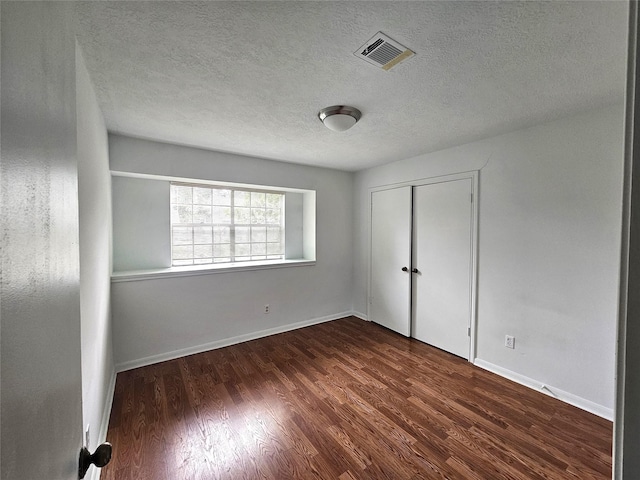 empty room with dark wood-type flooring and a textured ceiling