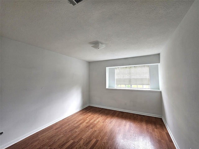 empty room with a textured ceiling and dark hardwood / wood-style floors