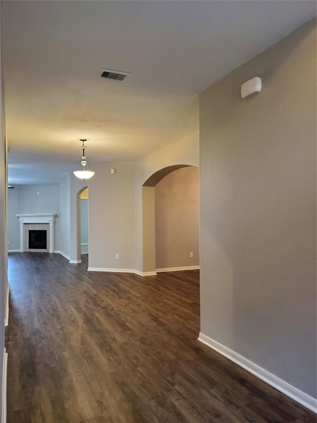 unfurnished living room featuring a tile fireplace and dark hardwood / wood-style floors