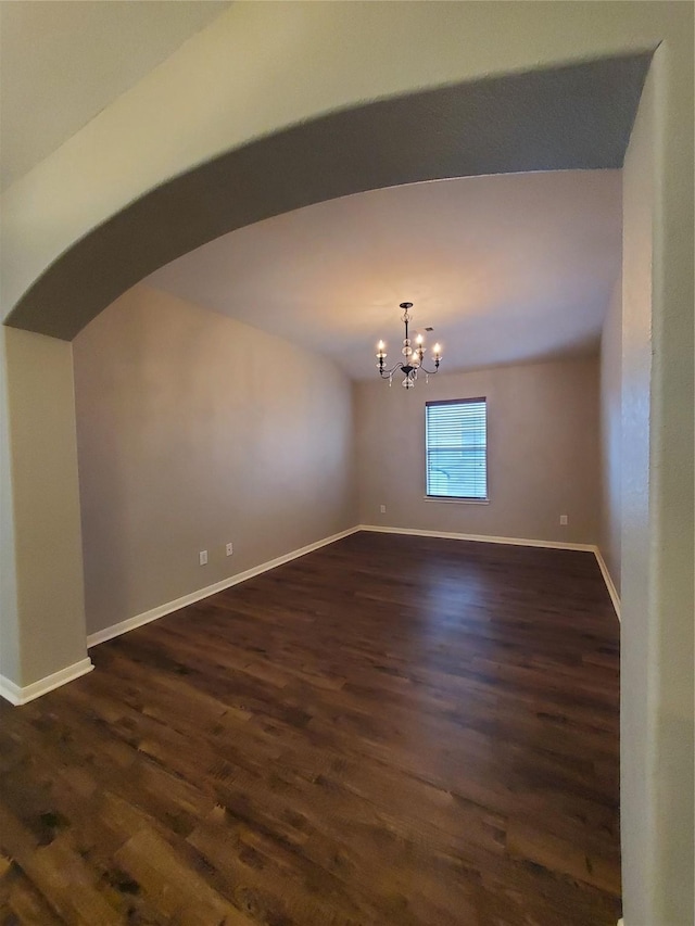 spare room featuring a chandelier and dark hardwood / wood-style floors