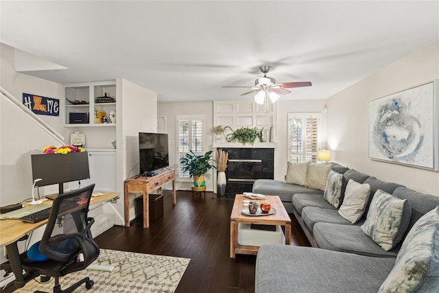 living room featuring a tile fireplace, ceiling fan, a healthy amount of sunlight, and dark hardwood / wood-style floors