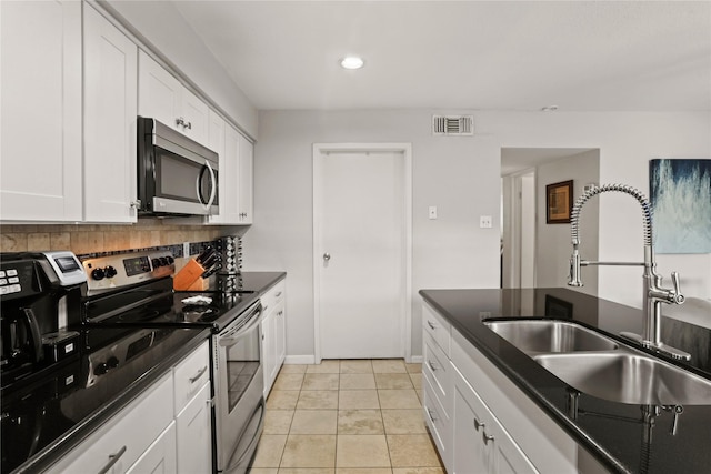 kitchen featuring appliances with stainless steel finishes, tasteful backsplash, sink, light tile patterned floors, and white cabinets