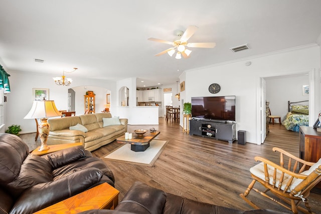 living room featuring ceiling fan with notable chandelier, dark wood-type flooring, and ornamental molding