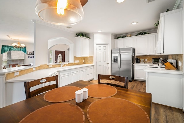 dining room featuring sink, dark hardwood / wood-style flooring, a chandelier, and ornamental molding