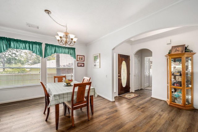 dining room with dark hardwood / wood-style flooring, ornamental molding, and an inviting chandelier