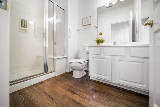 bathroom with wood-type flooring, vanity, toilet, and a shower with shower door