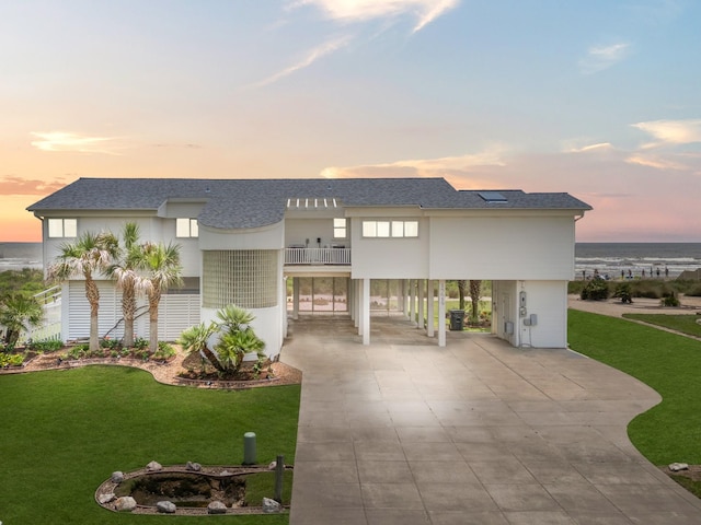 view of front of home with a carport, a balcony, and a yard