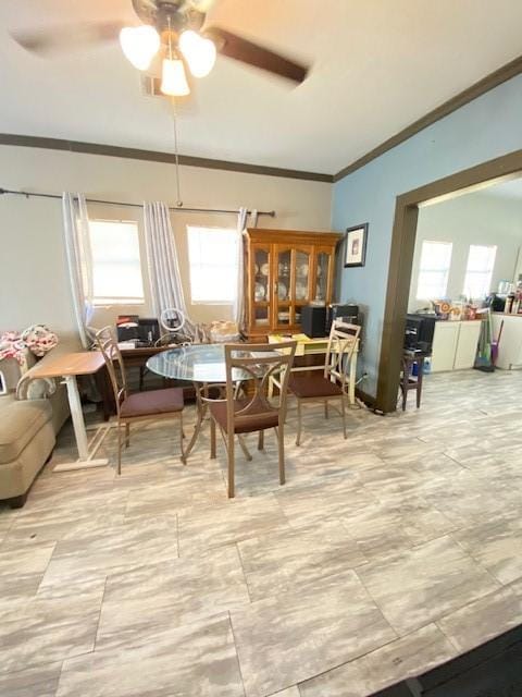 dining space with ceiling fan and ornamental molding