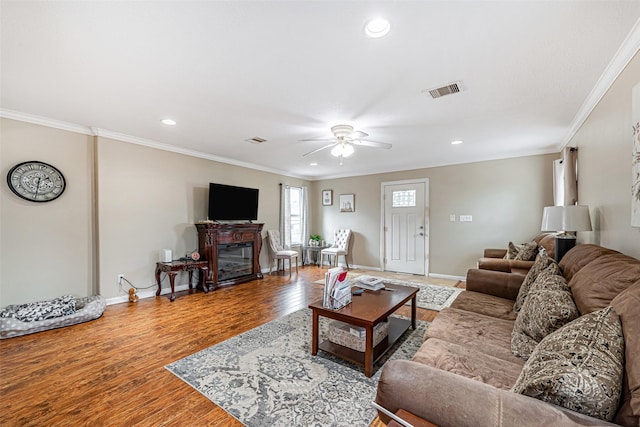 living room with hardwood / wood-style flooring, ceiling fan, and crown molding