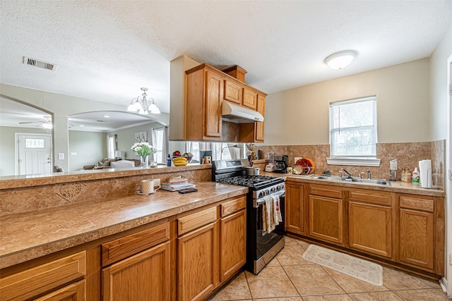 kitchen featuring decorative backsplash, sink, ceiling fan with notable chandelier, and stainless steel gas range