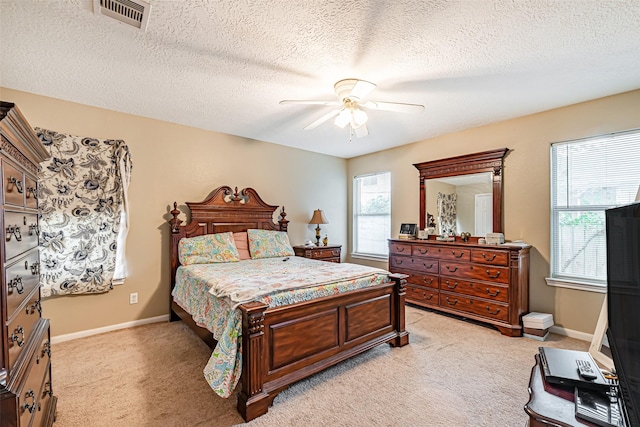 bedroom featuring ceiling fan, light carpet, and a textured ceiling