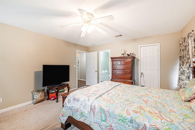 bedroom with ceiling fan, carpet, ensuite bathroom, and a textured ceiling