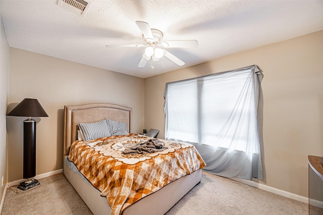 carpeted bedroom with ceiling fan and a textured ceiling