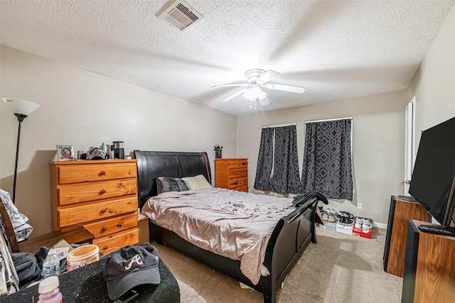 bedroom with ceiling fan, light carpet, and a textured ceiling