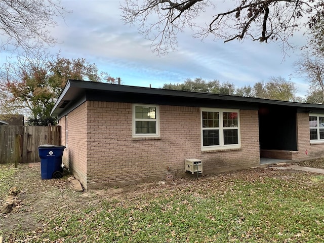 view of side of property featuring brick siding and fence