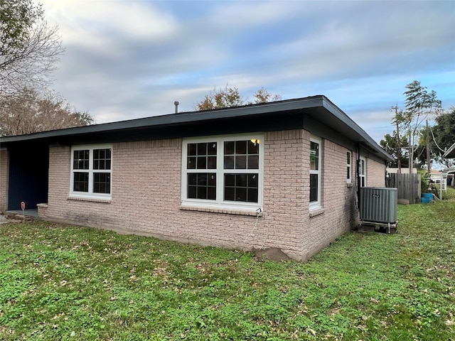 view of home's exterior featuring a yard, brick siding, and central AC unit