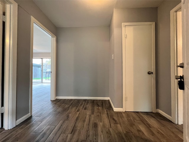 hallway featuring dark wood finished floors and baseboards