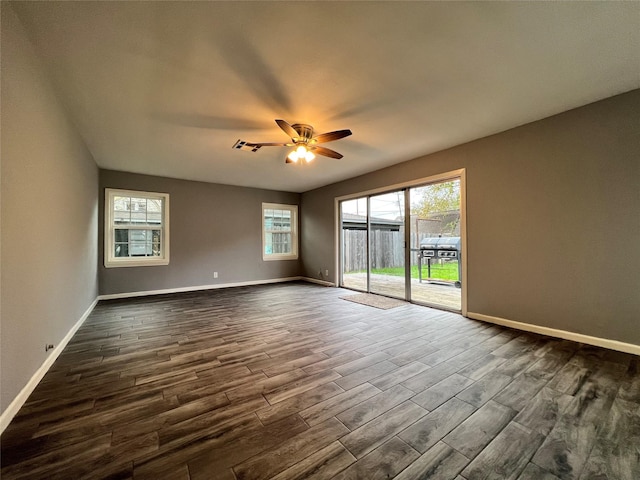 empty room featuring visible vents, baseboards, dark wood-type flooring, and ceiling fan