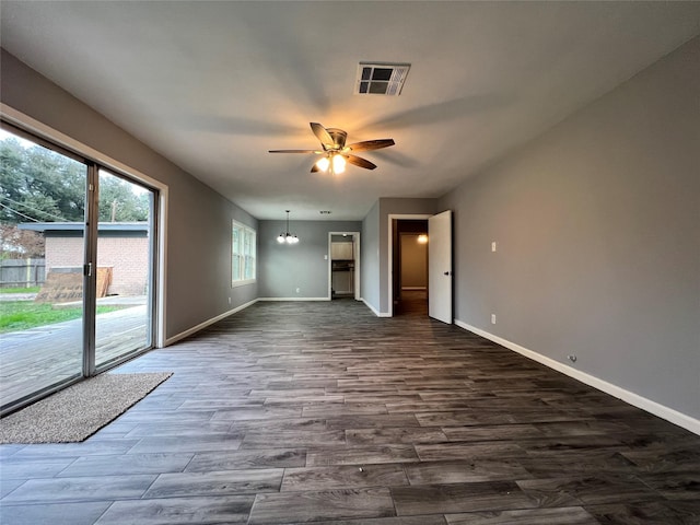 unfurnished living room with dark wood finished floors, visible vents, ceiling fan with notable chandelier, and baseboards