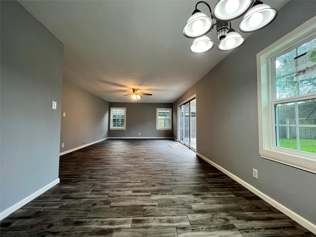 empty room featuring baseboards, dark wood-type flooring, and ceiling fan with notable chandelier