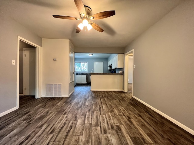 unfurnished living room featuring visible vents, dark wood-type flooring, and baseboards