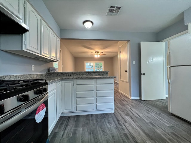 kitchen featuring visible vents, a peninsula, freestanding refrigerator, under cabinet range hood, and stainless steel gas stove